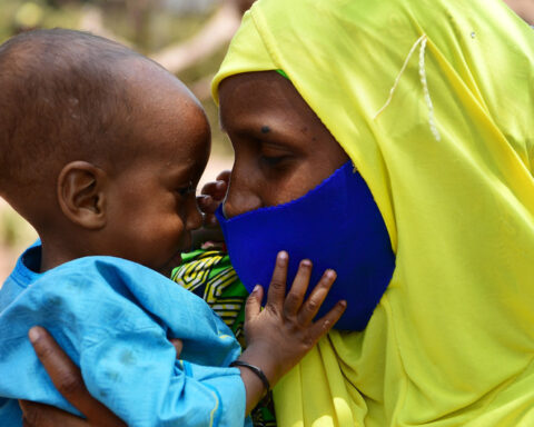 A baby plays with her mother’s mask