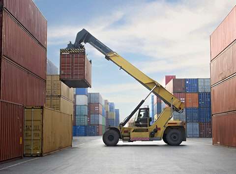 Crane lifting up container in a port.