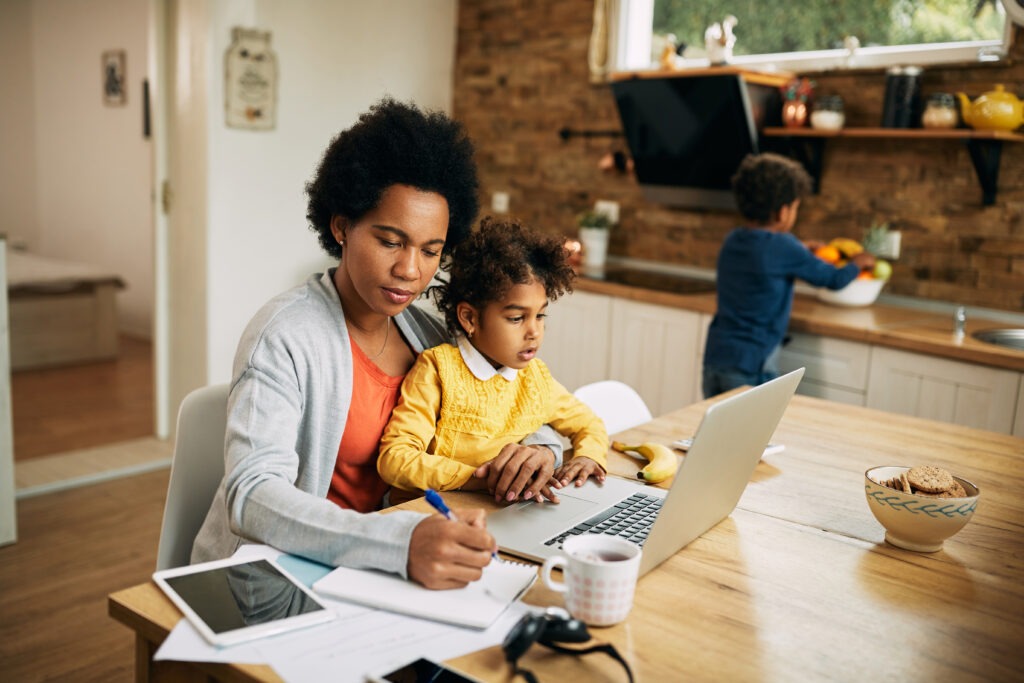 Black,Working,Mother,Taking,Notes,While,Daughter,Is,Sitting,On