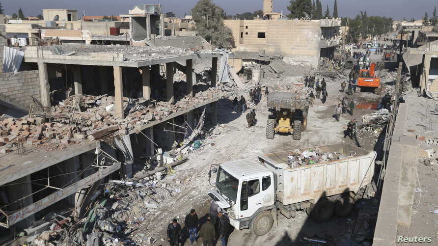 Residents inspect damage at a site hit by one of three explosive trucks, in the YPG-controlled town of Tel Tamer, Syria