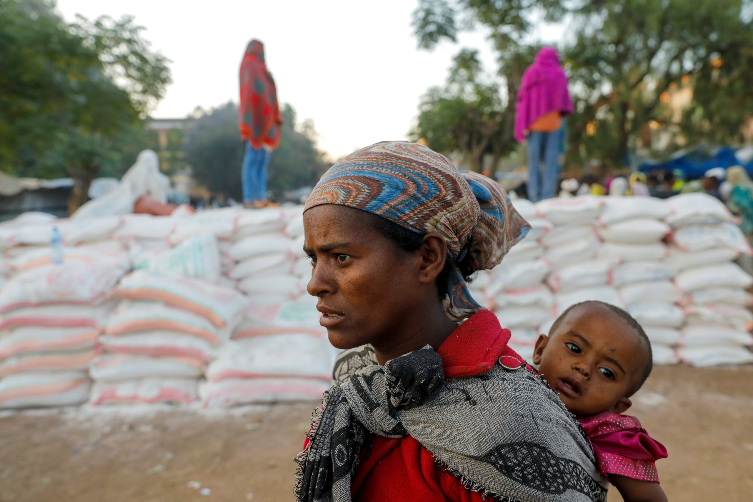 Woman carries an infant as she queues in line for food, at the Tsehaye primary school, in Shire