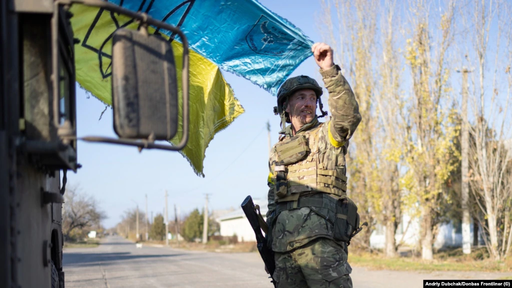 A soldier holds a weathered Ukrainian flag