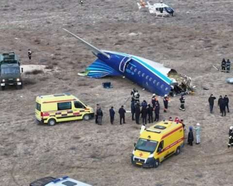 a plane crashed in a field with people around it