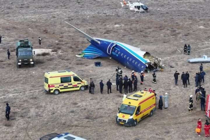 a plane crashed in a field with people around it