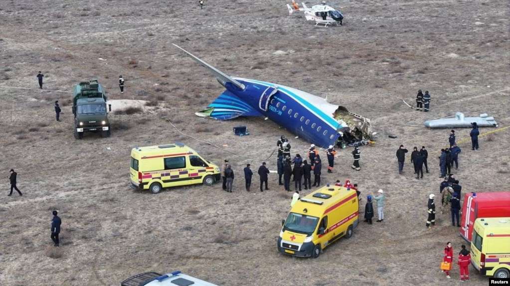 a plane crashed in a field with people around it